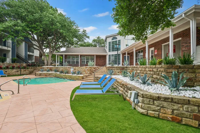 Relaxing outdoor lounge area with shaded seating and a view of the pool at a Plano, TX apartment community.