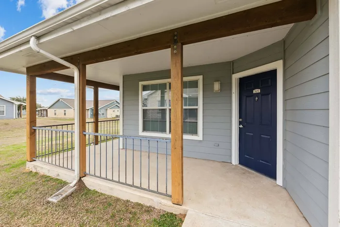 Inviting front porch with wooden columns, landscaping, and blue accents at Crescent Village in Elgin, TX