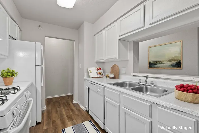 Modern kitchen with stainless steel appliances, white cabinetry, and granite countertops at Ovation Apartments in Austin, TX.