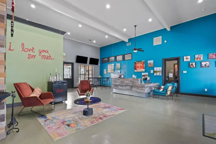 Community lounge with modern fireplace, velvet seating, and artistic decor at Ovation Apartments in Austin, TX, offering luxury amenities.