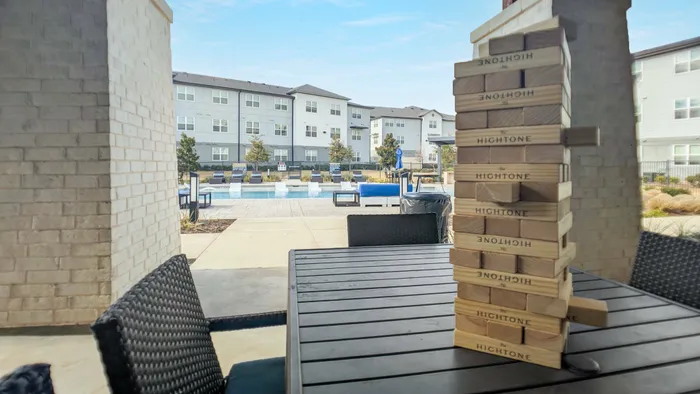 Shaded patio seating and table with elevated firepits and yard games