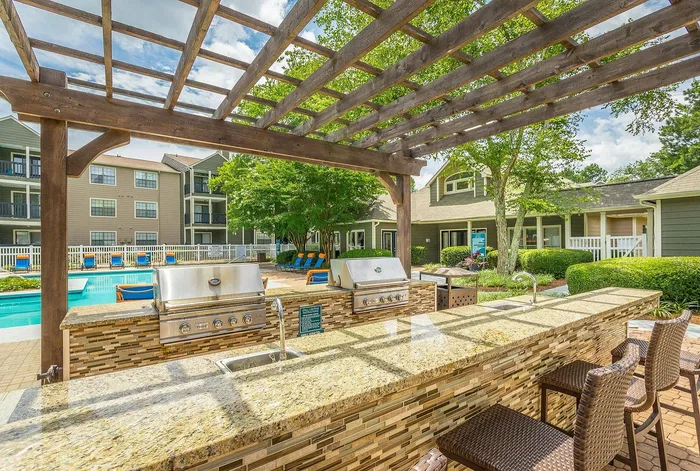 BBQ and picnic tables under shade trees at Avenues of Kennesaw in Kennesaw, GA