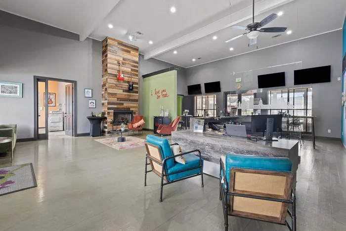 Community lounge with modern fireplace, velvet seating, and artistic decor at Ovation Apartments in Austin, TX, offering luxury amenities.