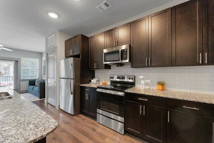 State-of-the-art kitchen with a large island and spacious open living room at Discovery Park in Denton, Texas.