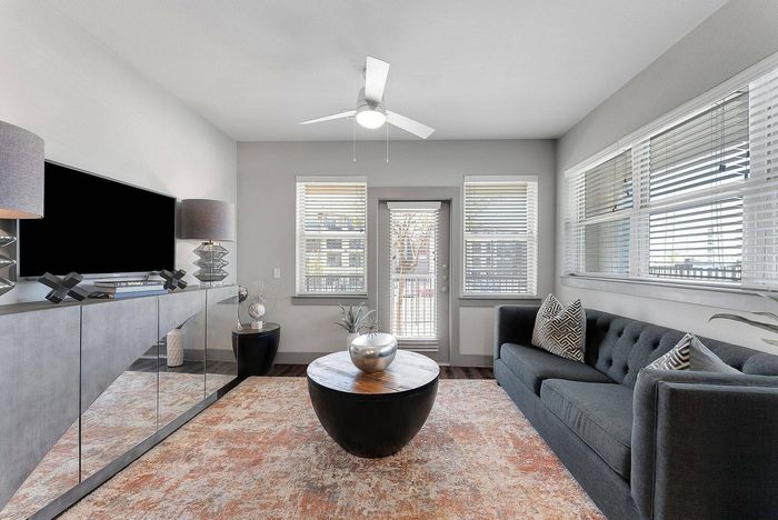 Modern living room with large windows, gray sofa, and round wooden coffee table