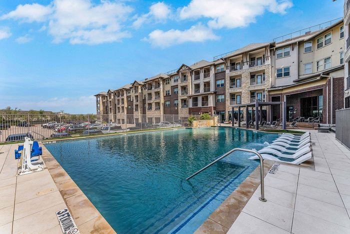 Resort-style swimming pool surrounded by apartment buildings at Discovery Park in Denton, TX