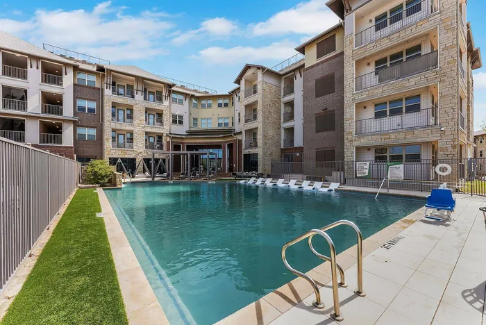 Resort-style swimming pool surrounded by apartment buildings at Discovery Park in Denton, TX