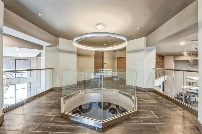 Upper floor hallway with glass railing and modern circular light fixture at Discovery Park Apartments