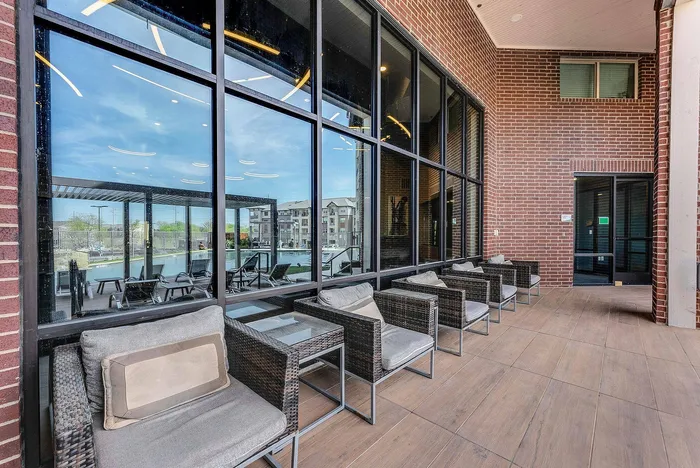 Patio with cushioned chairs and glass-top tables at Discovery Park Apartments in Denton, TX