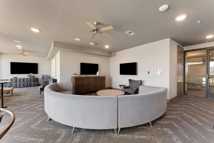 Resident media lounge with flat-screen TVs and multiple seating areas at Discovery Park Apartments in Denton, TX