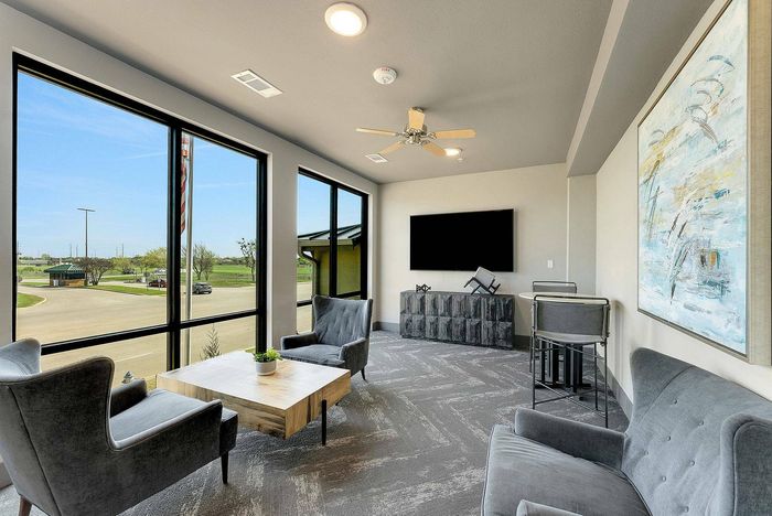 Corner lounge with gray chairs and wall art at Discovery Park Apartments in Denton, TX