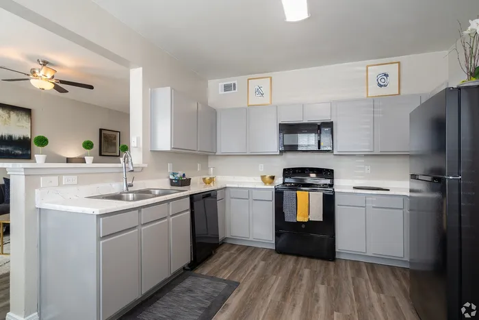 Modern kitchen with black appliances and light gray cabinets at Towne West Apartments