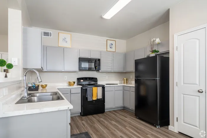 Open-concept kitchen with full appliances and modern cabinetry at Towne West Apartments