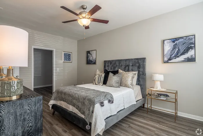 Elegant bedroom with tufted headboard and ceiling fan at Towne West Apartments in Houston
