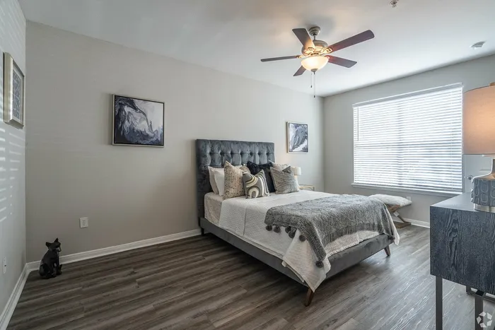 Elegant bedroom with tufted headboard and ceiling fan at Towne West Apartments in Houston
