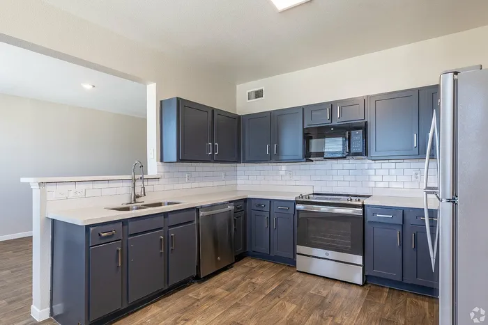 Modern kitchen with black appliances and light gray cabinets at Towne West Apartments