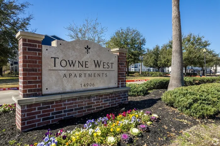 Towne West Apartments entrance sign with flowers in Houston, TX