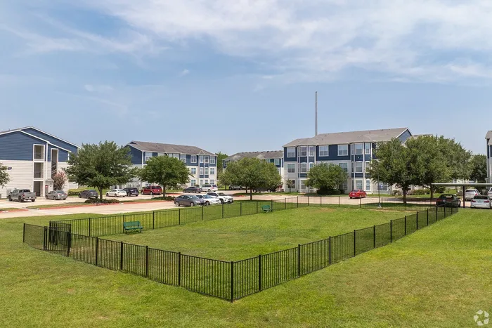 Large fenced dog park surrounded by apartment buildings at Towne West