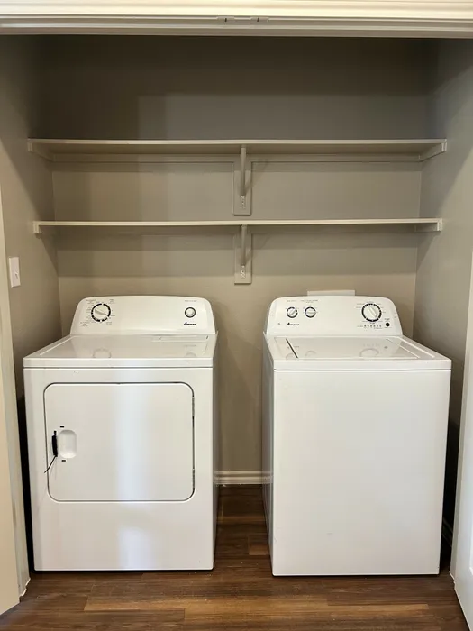 In-unit laundry room with a washer, dryer, and shelving at McDermott 55 in Plano, TX.