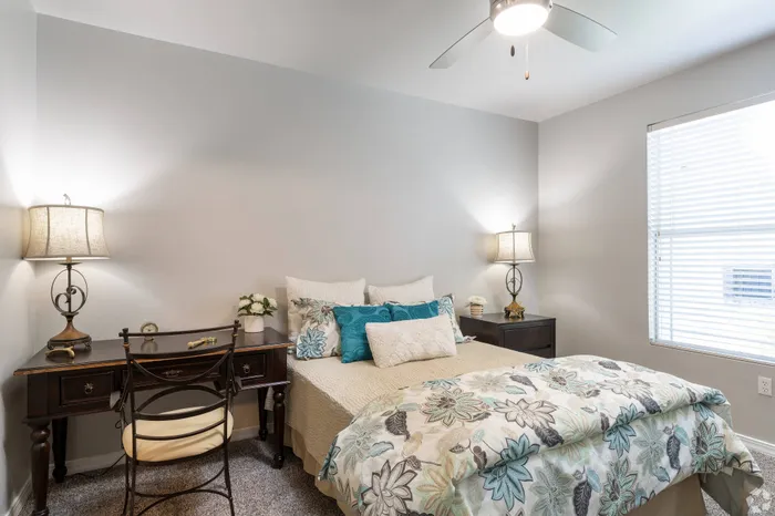 Bright and airy bedroom with large windows, cozy decor, and a ceiling fan at Lifestyles Hueco Estates in El Paso, TX.