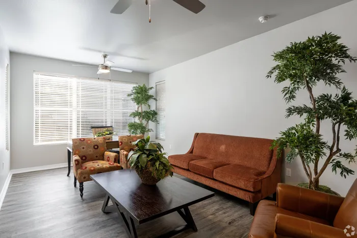 Open-concept living room with modern decor, ceiling fans, and large windows at Lifestyles Hueco Estates in El Paso, TX.