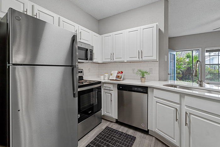Kitchen with vinyl floors, stainless-steel appliances, white quartz countertop