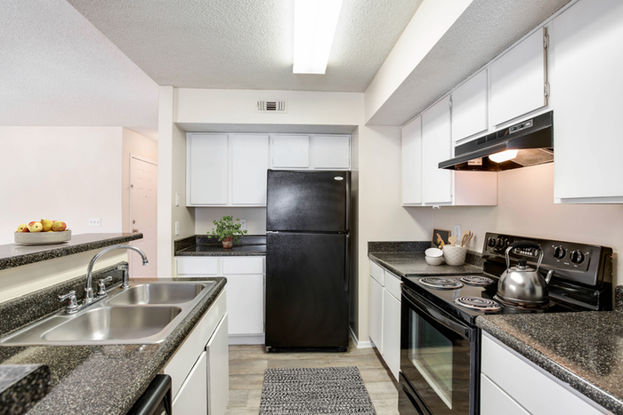 Kitchen with vinyl floors, black appliances, granite countertop