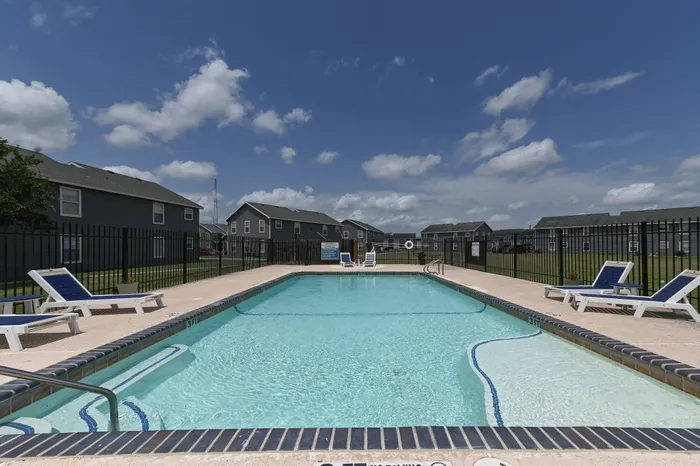 a sparkling swimming pool at Rancho de Luna Apartments surrounded by a resident walkway and in view of apartment buildings