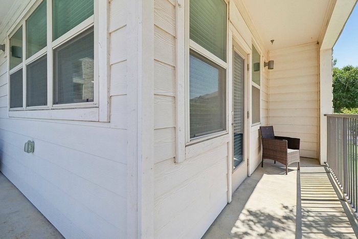 Covered balcony with cushioned seating and glass-top table at Discovery Park Apartments in Denton, TX