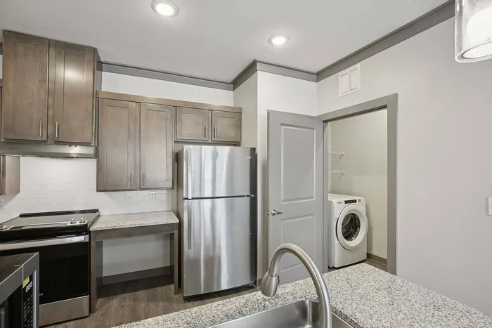 Modern kitchen with stainless steel appliances and in-unit washer and dryer at Cityscape Apartments Houston