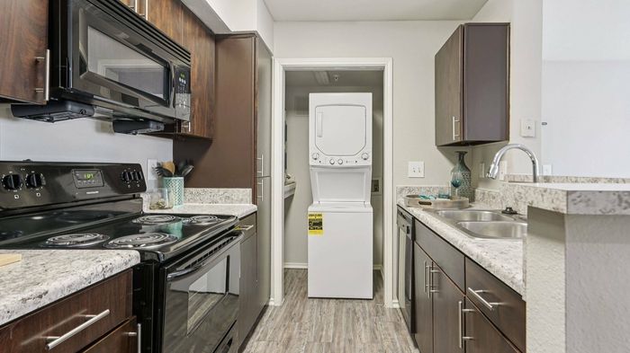 Spacious Oak Forest apartment kitchen with granite countertops and laundry appliances in Lewisville, TX