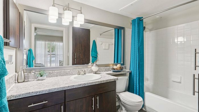 Modern bathroom with sleek vanity and large mirror at Oak Forest in Lewisville, TX