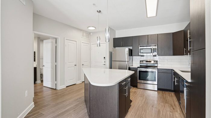 Sleek kitchen with island, quartz countertops, and stainless steel appliances at Addison Keller Springs, Addison TX.