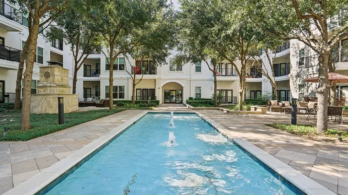 Resort-style swimming pool surrounded by lounge chairs at Addison Keller Springs in Addison, Texas