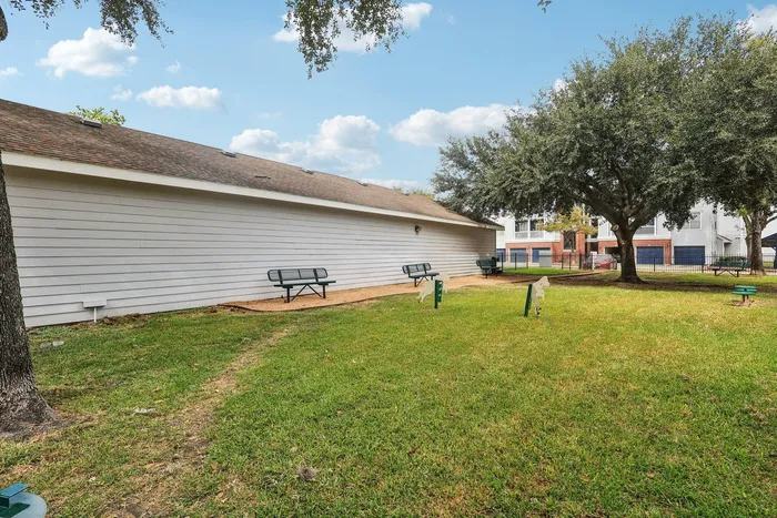 dog park with grass, a walking path, and comfortable benches