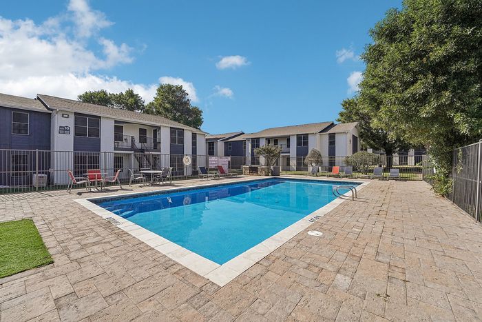 Sparkling swimming pool with lounge chairs and pergola shade structures in a Waco, TX apartment community.