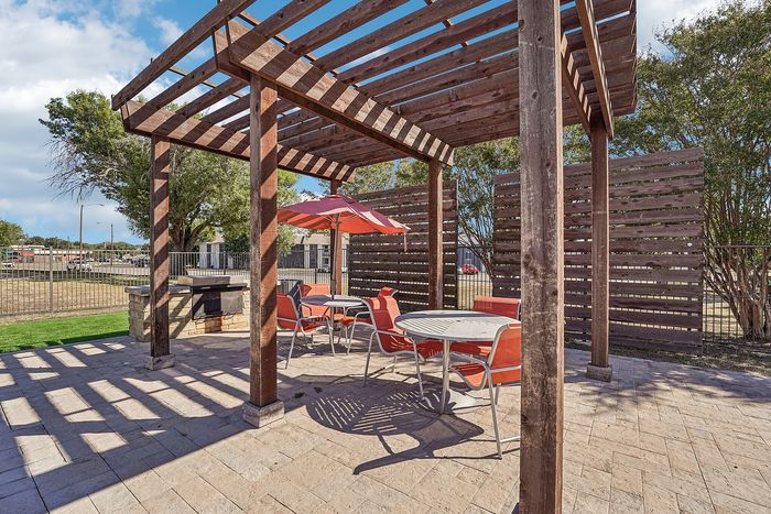 Outdoor fire pit surrounded by Adirondack chairs and adjacent to a playground in a Waco, TX apartment community.