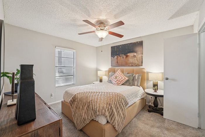 Cozy bedroom with a neutral palette, plush bedding, modern furniture, and a ceiling fan in a Waco, TX apartment.