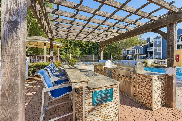 BBQ and picnic tables under shade trees at Avenues of Kennesaw in Kennesaw, GA