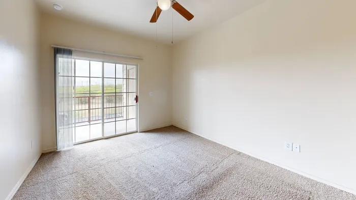 Bright living room with large windows, neutral walls, and wood-style flooring at Willowbend Apartments in San Antonio, TX.