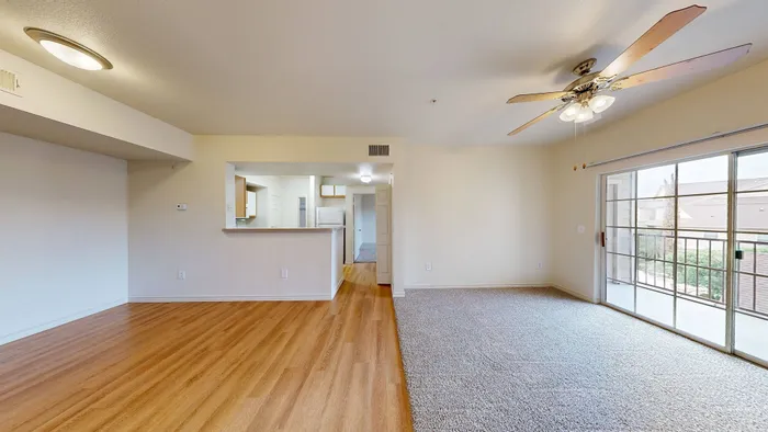 Bright living room with large windows, neutral walls, and wood-style flooring at Willowbend Apartments in San Antonio, TX.