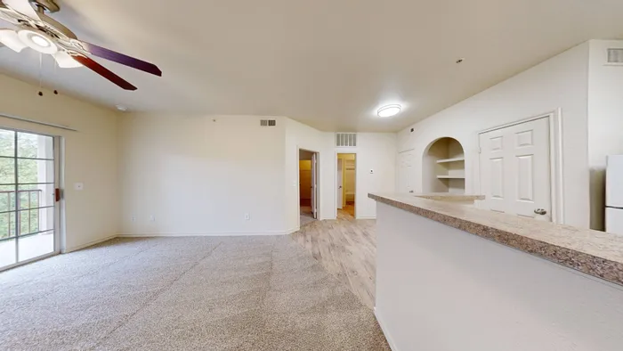Bright living room with large windows, neutral walls, and wood-style flooring at Willowbend Apartments in San Antonio, TX.