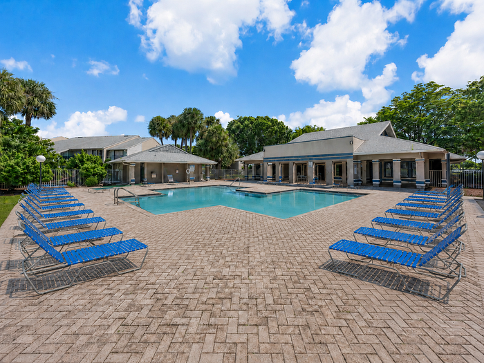 Swimming pool with blue lounge chairs and lake views at Clipper Cove Apartments.