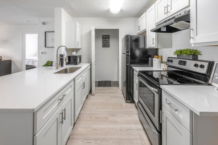 upgraded state of the art kitchen with white counters and cabinets and stainless steel appliances