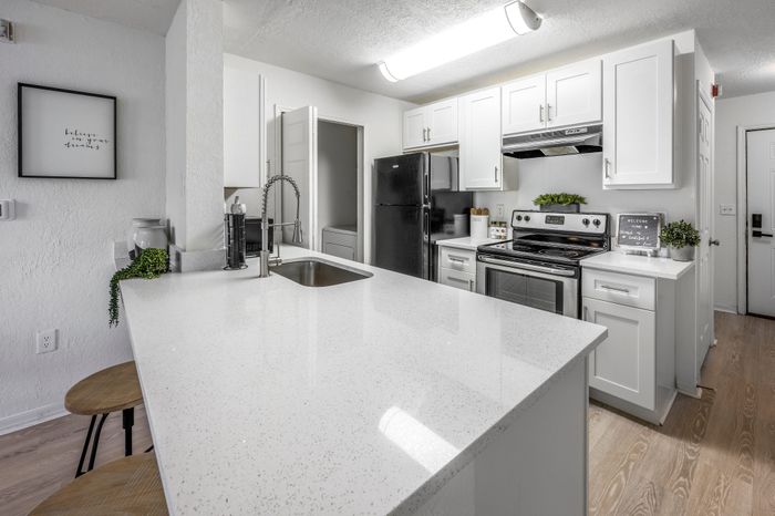upgraded state of the art kitchen with white counters and cabinets and stainless steel appliances