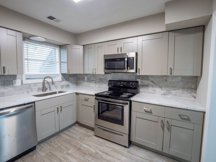Large kitchen with stainless steel appliances, tile backsplash