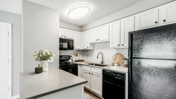 Black appliances, white cabinetry, white tile backsplash, undermount gooseneck faucet