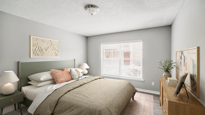 Bedroom with hardwood floors, rug, wooden dresser, queen size bed with green headboard, green nightstand and table lamp, large window