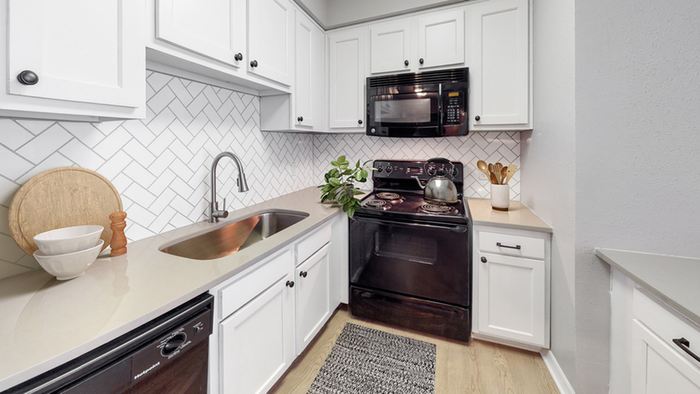 Kitchen, hardwood flooring, black stove, black built in microwave, white cabinetry, white  tile backsplash, under mount sink with gooseneck faucet