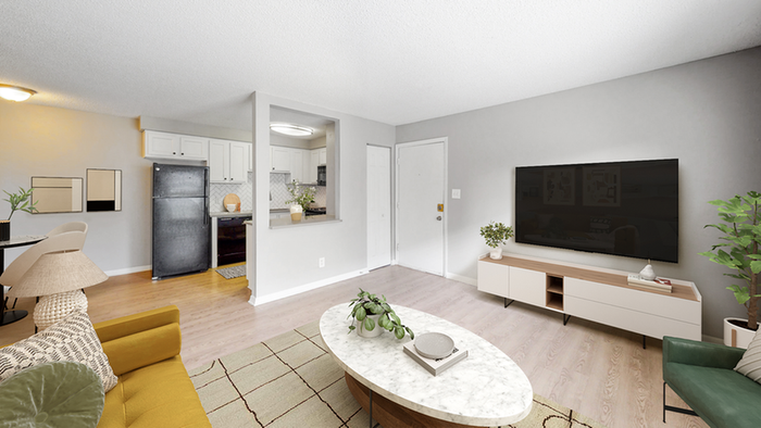 Hardwood style flooring, marble round coffee table, Flat screen TV, black refrigerator, green chair
